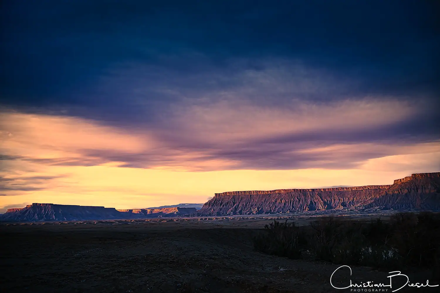 Sonnenaufgang an der North- und South Caineville Mesa Beeindruckendes Landschaftsfoto mit farbenfrohem Himmel über der North Caineville Mesa und der South Caineville Mesa.