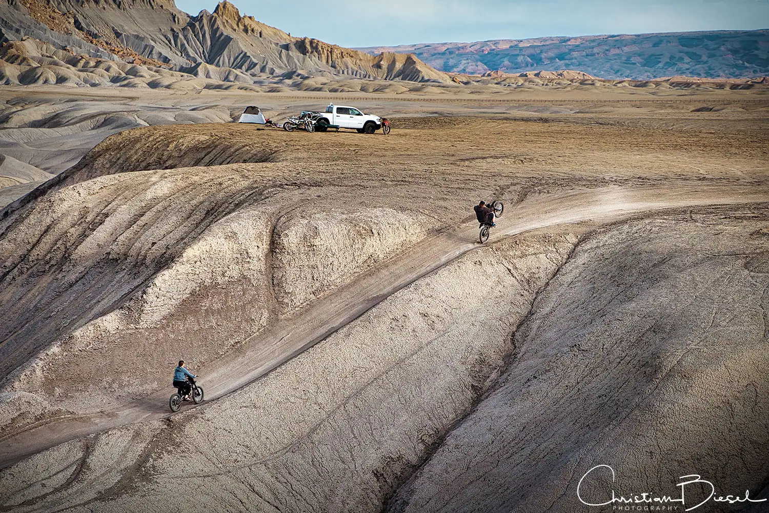 Abenteuerliche Mountainbiker im Wüstengebiet der Swing Arm City, Utah Fahrradfahrer beim Downhill-Fahren in karger Wüstenlandschaft, ultimatives Outdoor-Erlebnis. Swing Arm City, Utah.
