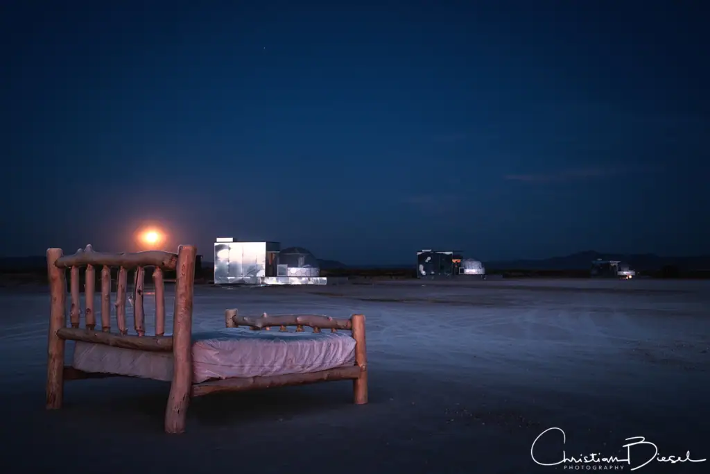 Vollmond über dem Outpost X. Mit einem Bett aus Holzstämmen auf dem Mud Lake im Vordergrund und drei Zen Domes im Hintergrund.